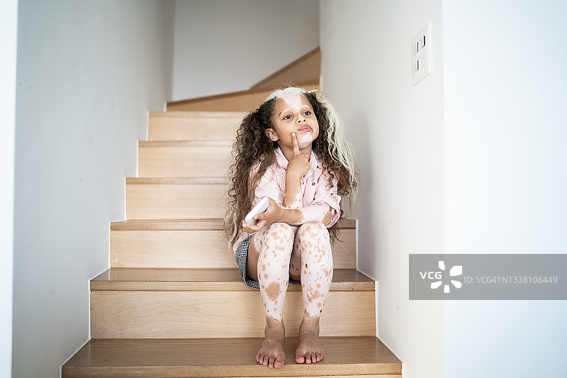 患有花斑病的女孩在家思考并拿着智能手机图片素材