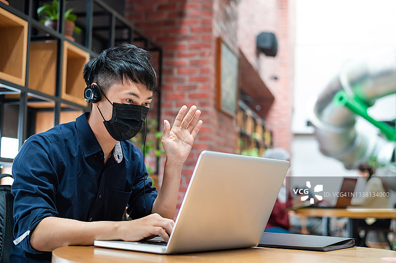 中国籍青年创业者在联合办公室内戴防护口罩，通过笔记本电脑与商业伙伴和客户进行视频通话图片素材