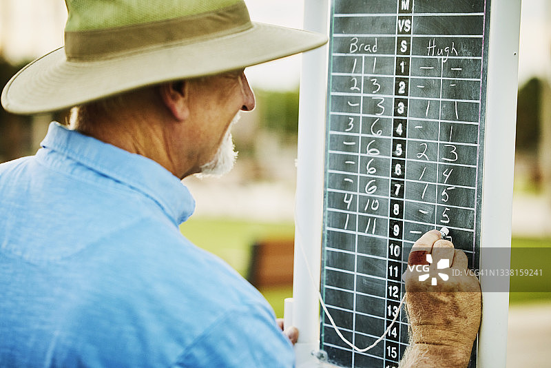 夏季傍晚，年长的草地保龄球手在比赛中于记分牌上书写图片素材