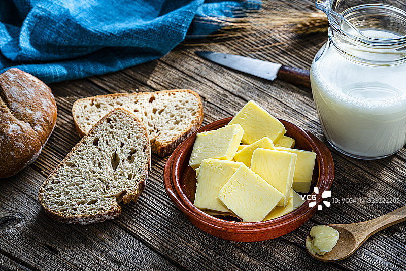 木桌上的黄油片、牛奶罐和面包图片素材