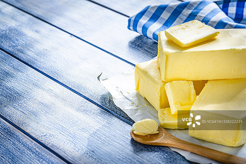 蓝色桌子上的黄油块和碎片。复制空间图片素材
