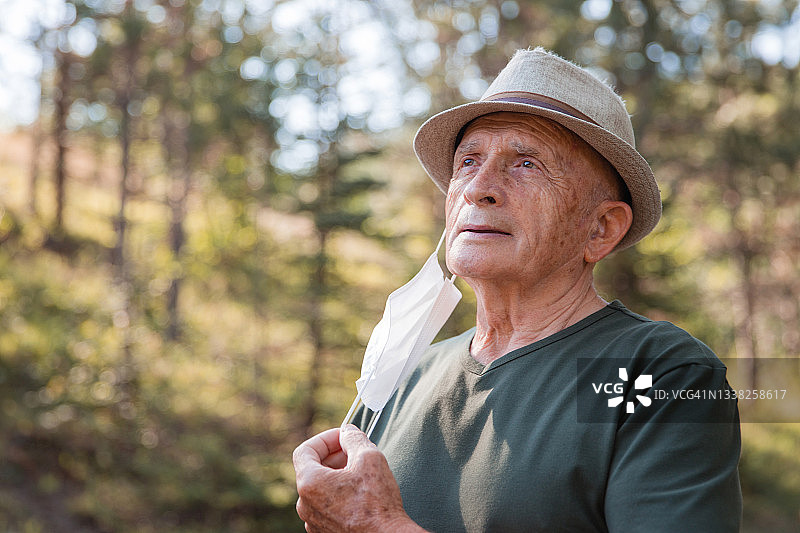 摘下口罩后感到轻松愉快的快乐老年男子图片素材