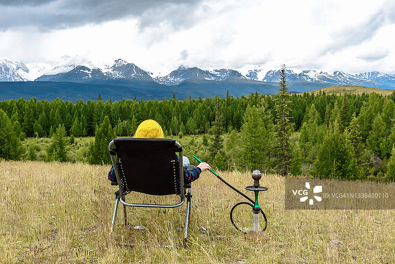 女人抽着水烟，欣赏着美丽的群山景色图片素材