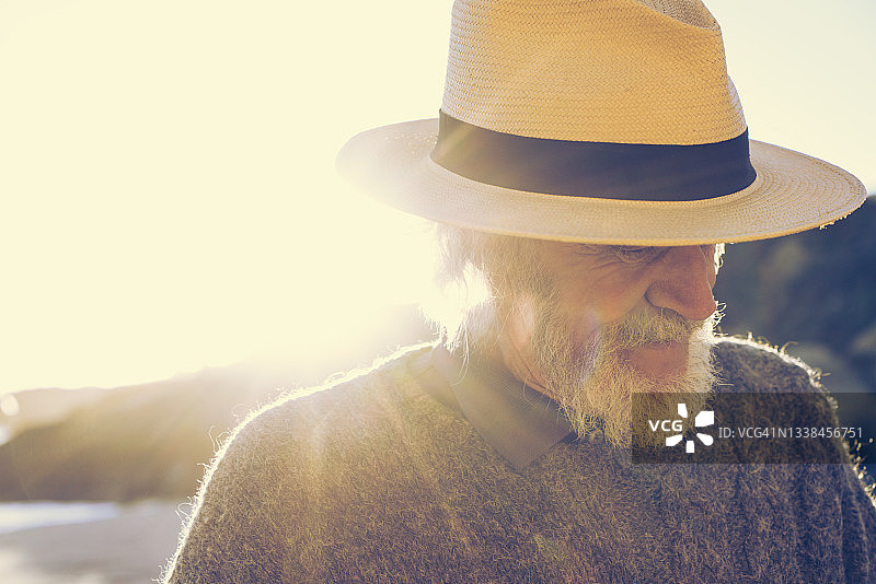 年长的男人在阳光明媚的海滩上戴着软呢帽图片素材