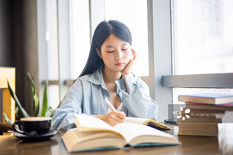 正在做作业和看书的年轻学生图片素材