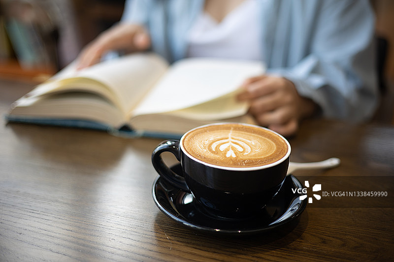 年轻女人喝咖啡并读书图片素材