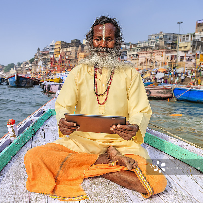 圣徒在瓦拉纳西恒河的船上使用平板电脑图片素材