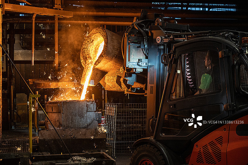 用叉车将液态熔融金属倒入铸造模具中图片素材