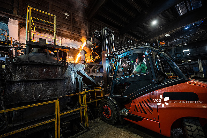用叉车将液态熔融金属倒入铸造模具中图片素材
