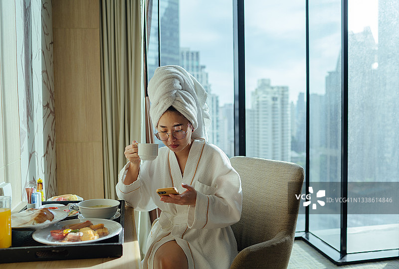 坐着，拿着咖啡杯，使用手机的女人图片素材