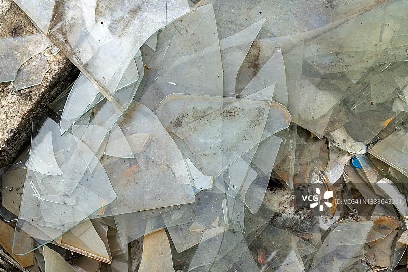 地面上散落着许多锋利的碎玻璃片和橙色树叶图片素材