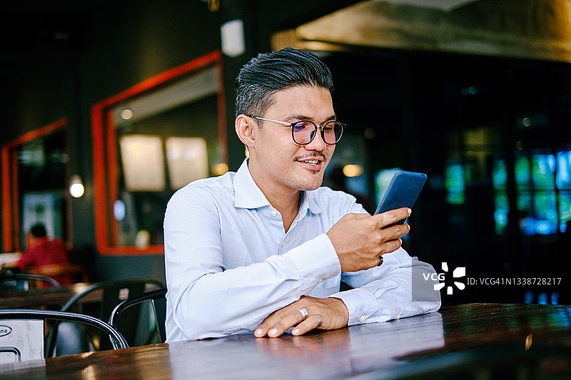 坐在咖啡馆中玩手机的资深高管男人肖像图片素材