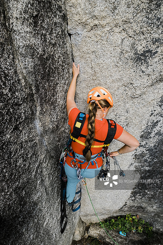 女攀岩者在辅助攀登时从安全带上取装备图片素材