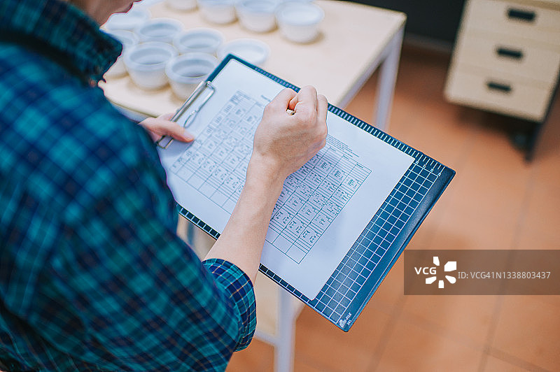 亚裔咖啡师品尝咖啡后在写字板上记录的高角度专业照片图片素材