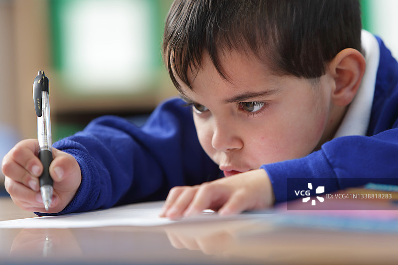 趴在桌子上写字的男学生图片素材