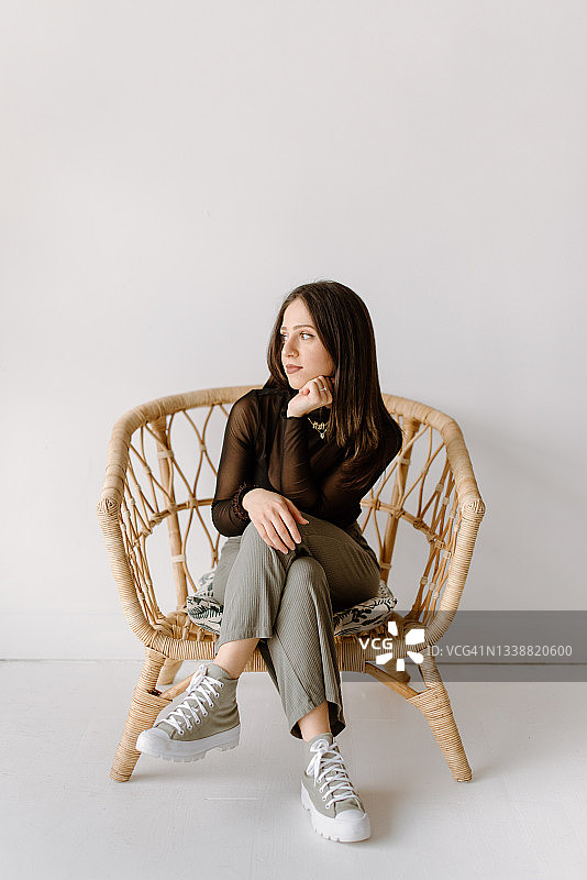 年轻女子坐在柳条椅上的工作室照片图片素材