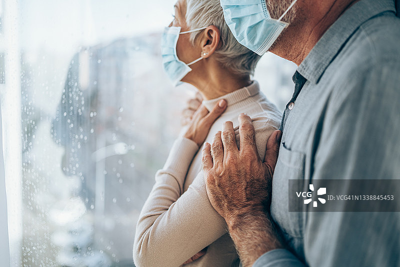 隔离在家中，隔窗向外看的焦虑老年夫妇图片素材