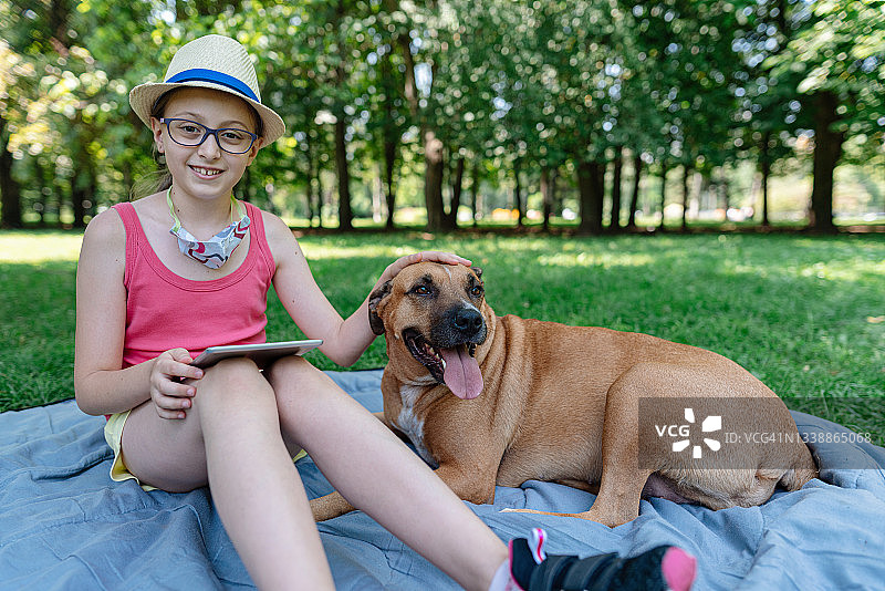 女孩和她的狗在公园里放松图片素材