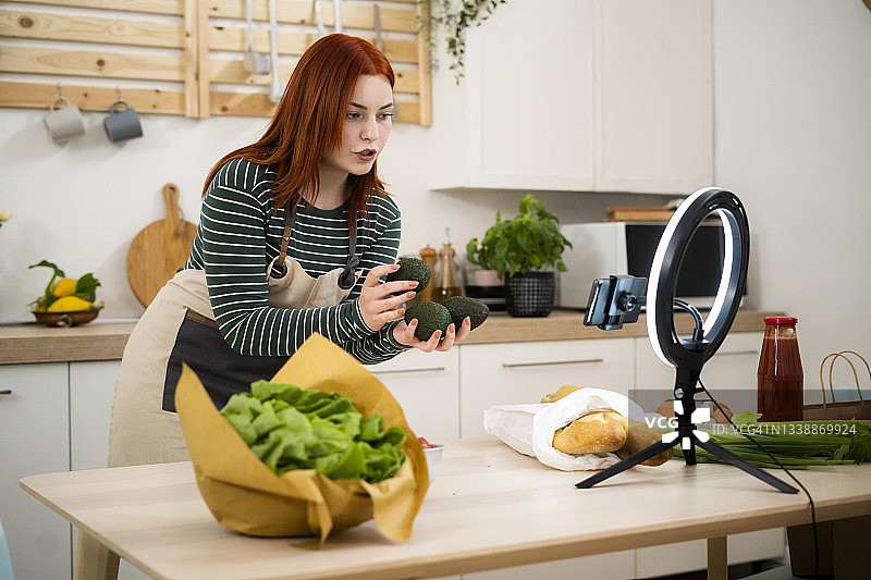 在家通过手机直播讲解蔬菜的女视频博主图片素材