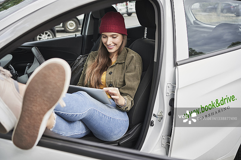 年轻女子坐在车里使用平板电脑图片素材