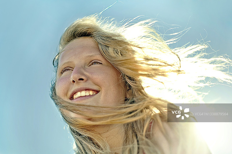 在晴朗天空下微笑的金发少女图片素材