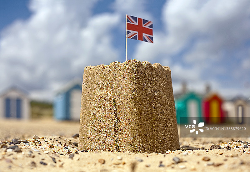 阳光明媚的日子里，沙滩上带有英国国旗的沙堡图片素材