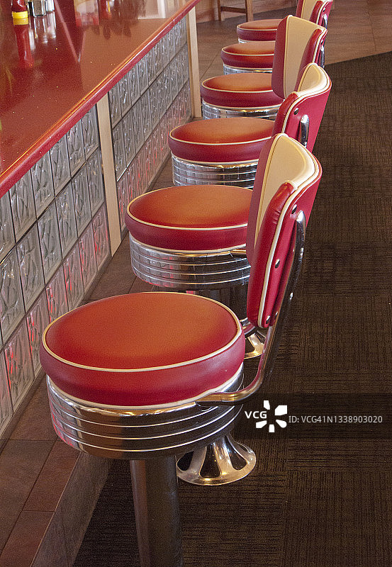 20世纪50年代复古餐厅的一排红色乙烯基苏打水吧凳图片素材
