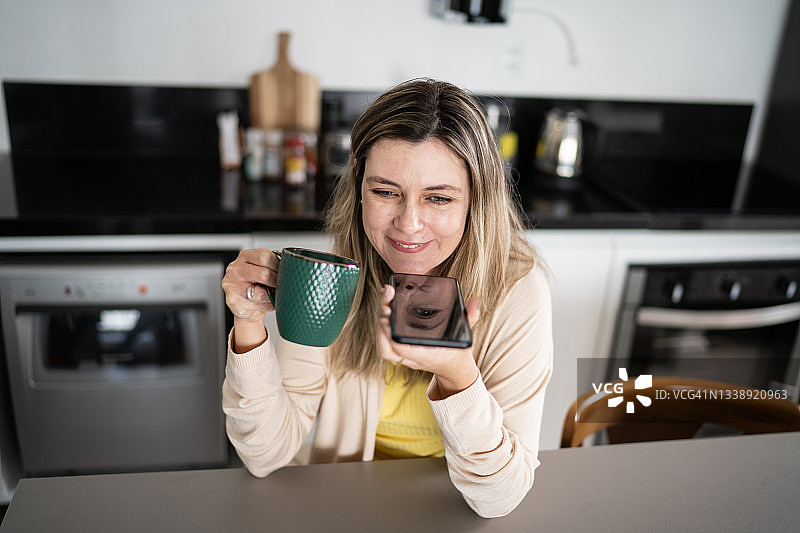 女人在家喝咖啡时用智能手机发送语音消息图片素材