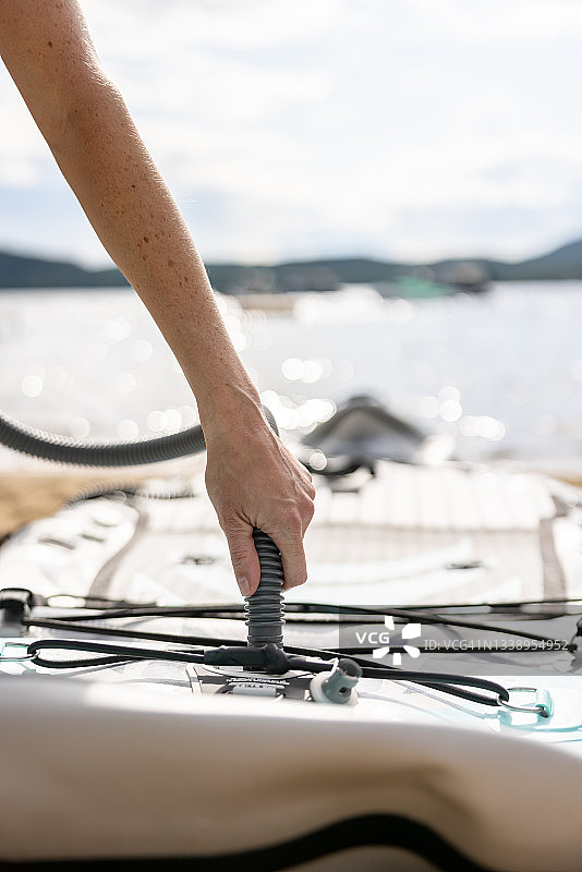 在魁北克夏季海滩上给桨板充气的女人图片素材