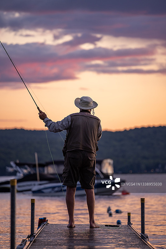年长的男人在日落时分飞蝇钓鱼图片素材