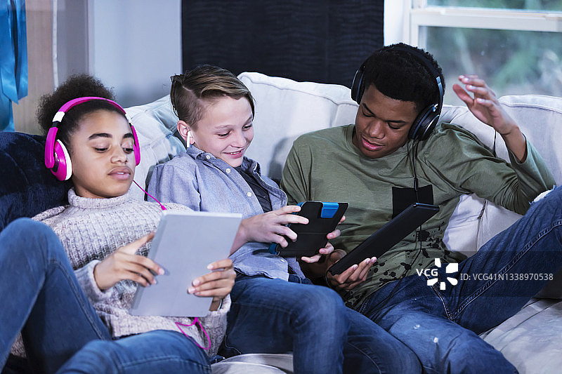 重组家庭中的三个孩子使用数位平板电脑图片素材