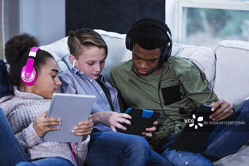 重组家庭中的三个孩子使用数位平板电脑图片素材