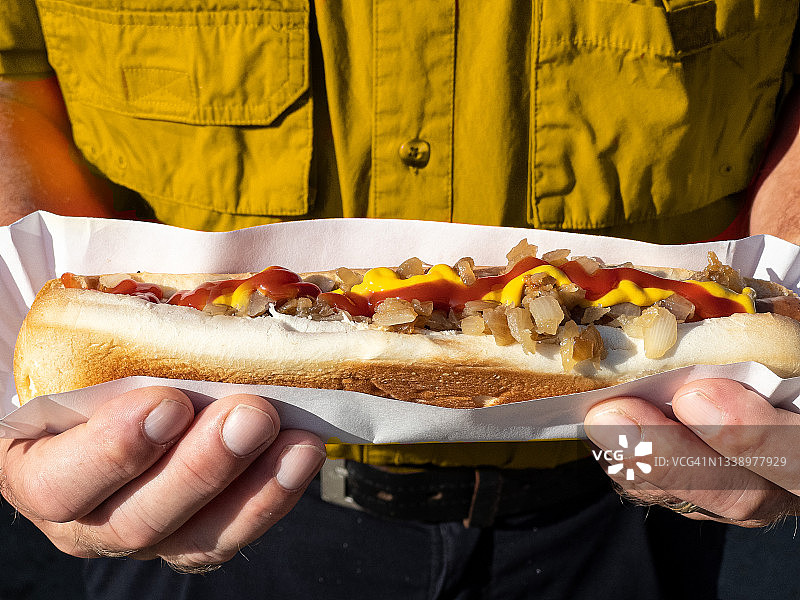 穿着黄色衬衫，拿着超长热狗的男人图片素材