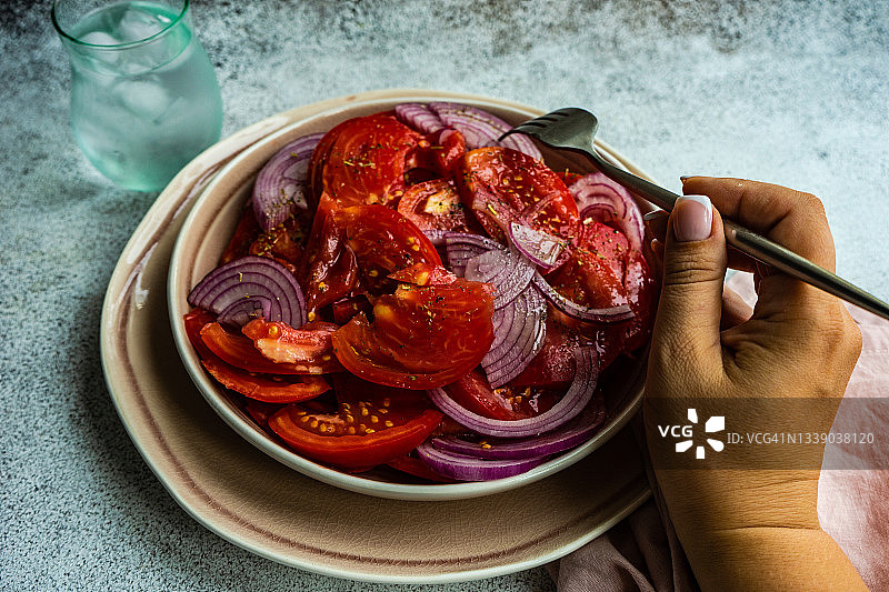 吃西红柿和红洋葱沙拉，配一杯冰水的女人图片素材