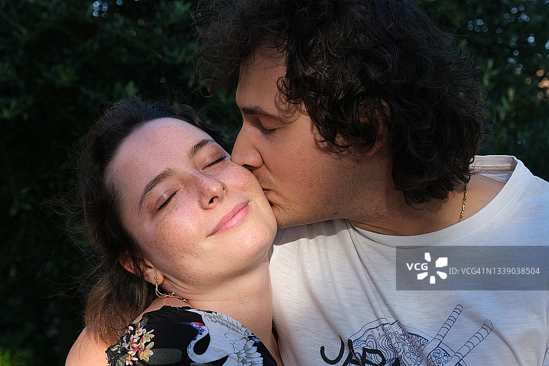 花园里男人亲吻女人脸颊的肖像图片素材