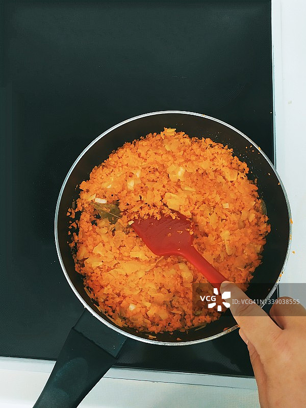 俯视：女人在炉子上烹饪胡萝卜丁图片素材