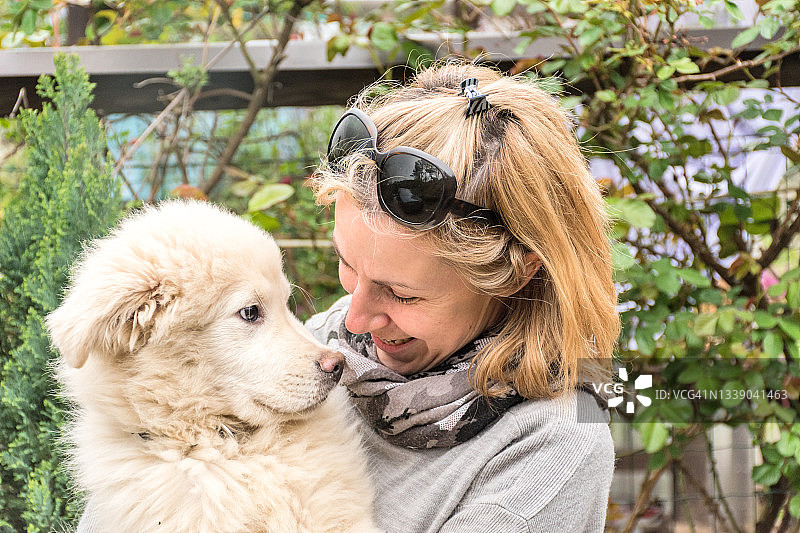 怀抱萨摩耶幼犬的微笑女人图片素材