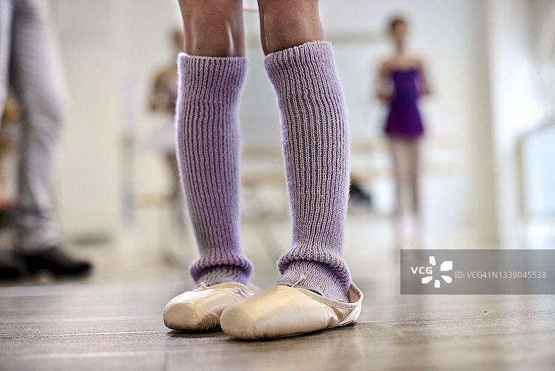 在舞蹈工作室里穿着护腿和芭蕾舞鞋的女孩的腿图片素材