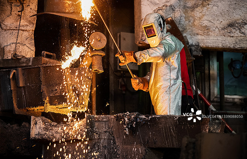 在铸造厂检查熔融金属的中年男冶金学家图片素材