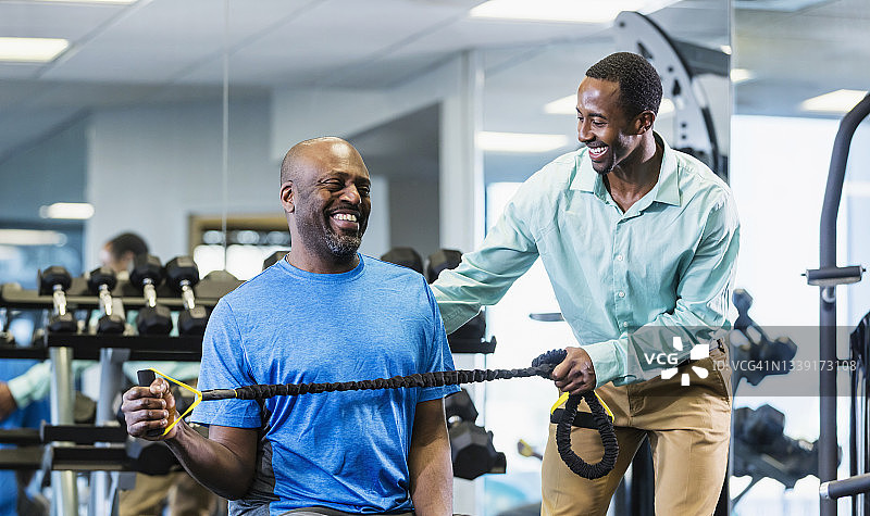 黑色理疗师帮助男人增强手臂力量图片素材