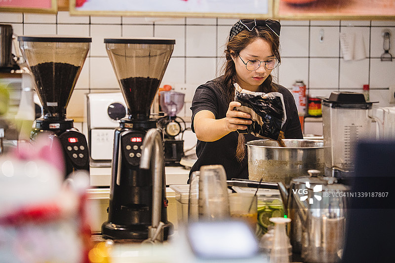 亚洲女咖啡师在吧台制作奶茶图片素材