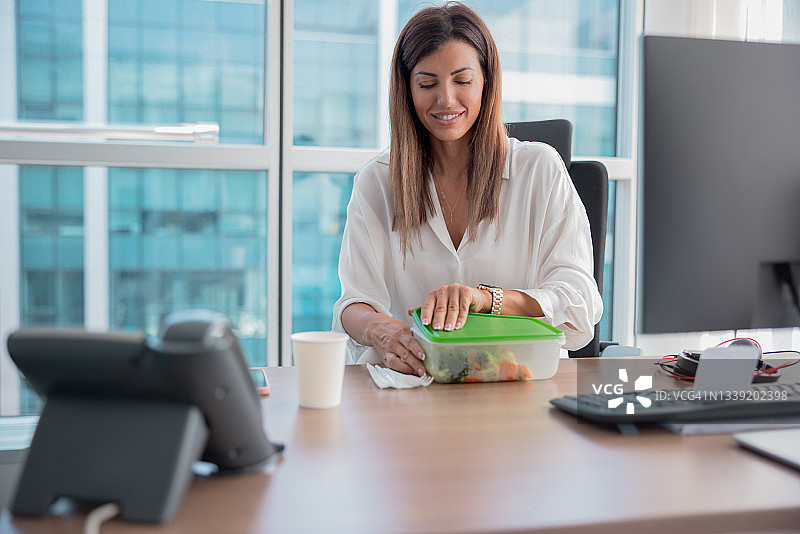 女商人午休时间，打开装有健康午餐的塑料盒图片素材
