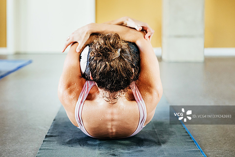 女人在瑜伽垫上屈膝抱胸图片素材