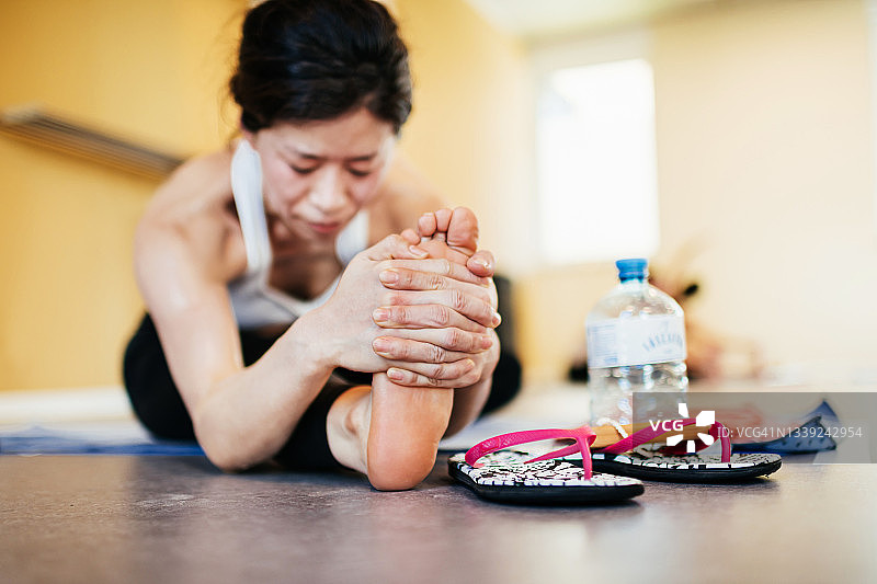 女子在高温瑜伽课上在地板上伸展身体图片素材