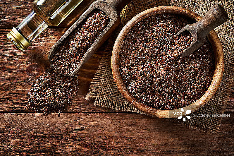 碗中的亚麻籽和木制背景上的亚麻籽油顶视图图片素材