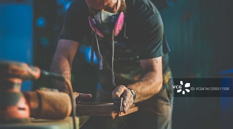 戴着呼吸器的男人进行木工和打磨施工项目图片素材