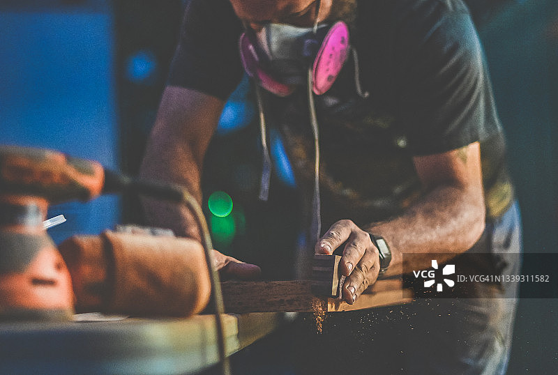 戴着呼吸器的男人进行木工和打磨施工项目图片素材