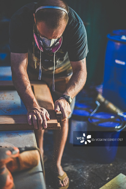 戴着呼吸器的男人进行木工和打磨施工项目图片素材