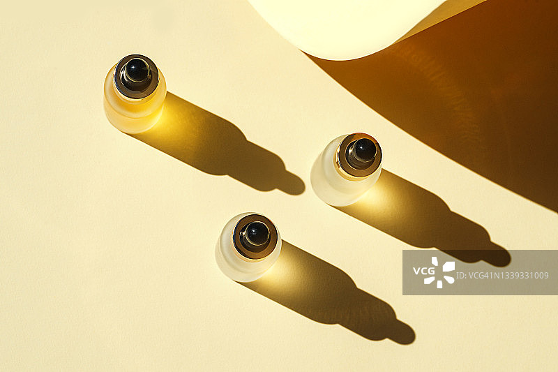 面部精华液的潮流美容概念，化妆品瓶中天然精油，滴管和柔和米色背景上的明亮阳光阴影图片素材