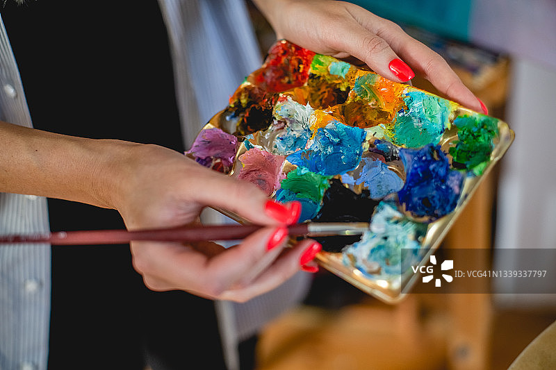 艺术工作室概念照：女性手持调色板和画笔的特写图片素材